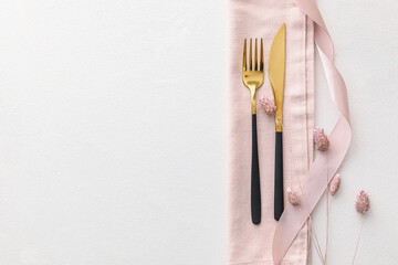 Elegant cutlery and lagurus flowers on light background