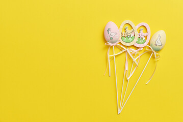 Easter decor in the form of eggs on a yellow background with copy space