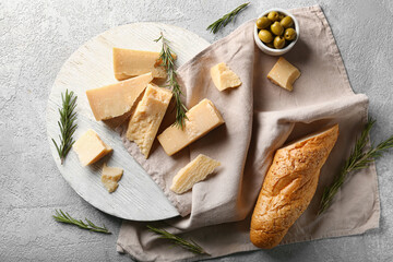 Wooden board with pieces of tasty Parmesan cheese and bread on grey background - Powered by Adobe