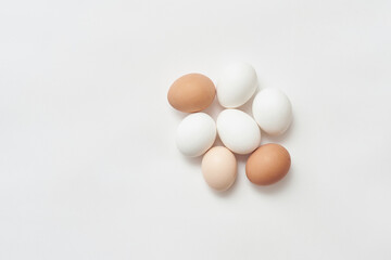 Various chicken eggs on white paper background