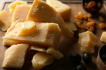 Board with pieces of tasty Parmesan cheese on table, closeup