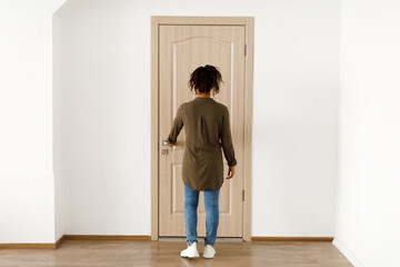 Fototapeta premium Back View Of Black Female Opening Apartment Door Standing Indoor