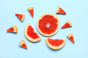 Slices of tasty ripe grapefruit on blue background
