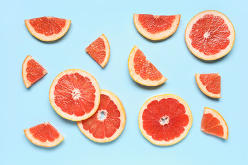 Slices of tasty ripe grapefruit on blue background