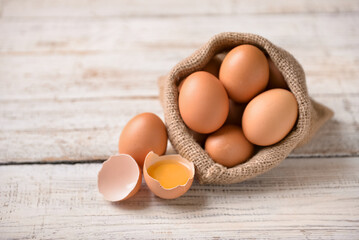 Sack with chicken eggs on white wooden background