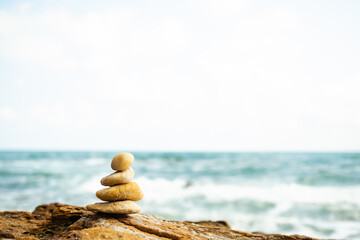 Stack Stone on sea at coast. balance and harmony pebble tower pyramid on big rock with blur wave and blue ocean. calm, meditate or aroma, vacation relax  therapy spa nature, wellness symbols concept.