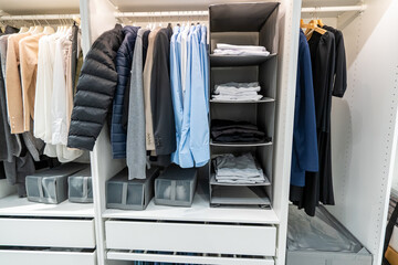 Modern style wooden cabinet with shirts, clothes and other items hanging on slide out rail. Wardrobe interior design concept.