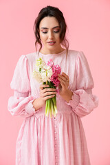 Pretty young woman with hyacinth flowers on pink background