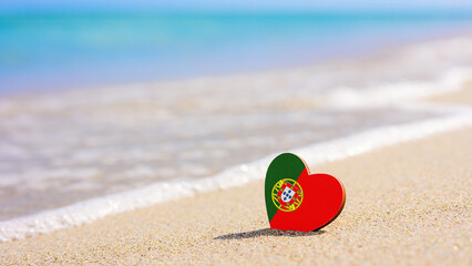 Fototapeta na wymiar Flag of Portugal in the shape of a heart on a sandy beach. The concept of the best vacation in Portugal