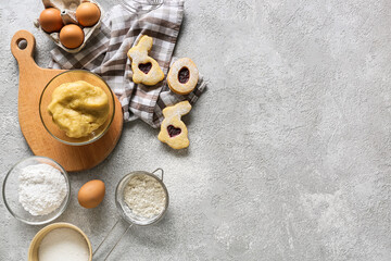 Bowl with dough and ingredients for preparing Easter cookies on grey background