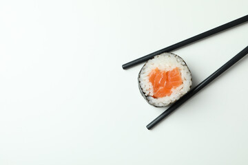 Chopsticks with maki on white background, space for text