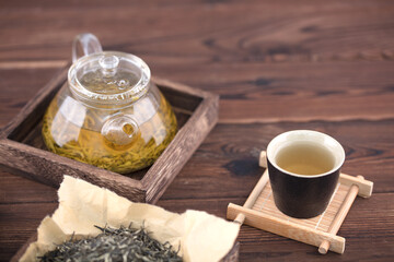 A pot of green tea and some tea are on the table