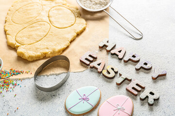Fototapeta na wymiar Text HAPPY EASTER made of wooden letters and tasty cookies on light background