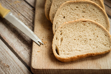 Sliced ​​fresh bread and cutting knife on rustic table