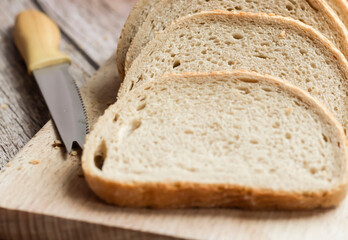 Sliced ​​fresh bread and cutting knife on rustic table