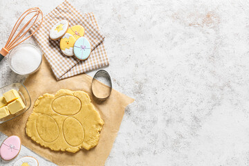 Fresh dough and tasty Easter cookies on light background