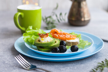Healthy breakfast. Sandwich with smoked salmon, avocado cheese on lettuce salad leaves and coffee