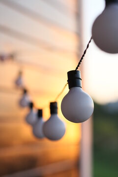 Garland of white light bulbs hanging on  wooden terrace in summer evening