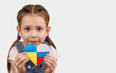 The little girl calls to Stop war, holding heart in the colors of the flag of Ukraine and Russia. Ukrainian and Russian flags together in heart. Grey background. Copy Space. No war. Stop war.