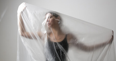Woman wrapped in plastic sheet. Studio shot. Woman and mental health concept.