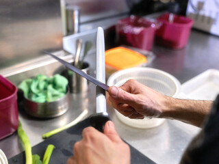 Cook sharpening kitchen knives in a restaurant