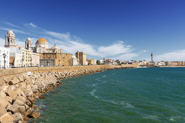 Fototapeta na wymiar The Atlantic coast in Cadiz with the Santa Cruz Cathedral and the San Roque stronhold