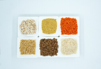 Cereals in white tiny plates on a white background. barley noodle, oat, green lentil, bulgur, red lentil, rice