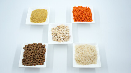 Cereals in white tiny plates on a white background. oat, green lentil, bulgur, red lentil, rice