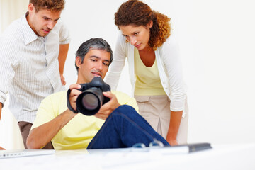 Photographers looking at pictures in camera. Male photographer showing pictures to his colleagues in his camera.