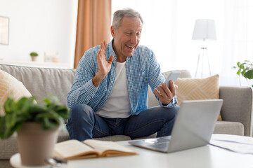 Smiling mature man waving hand using mobile phone