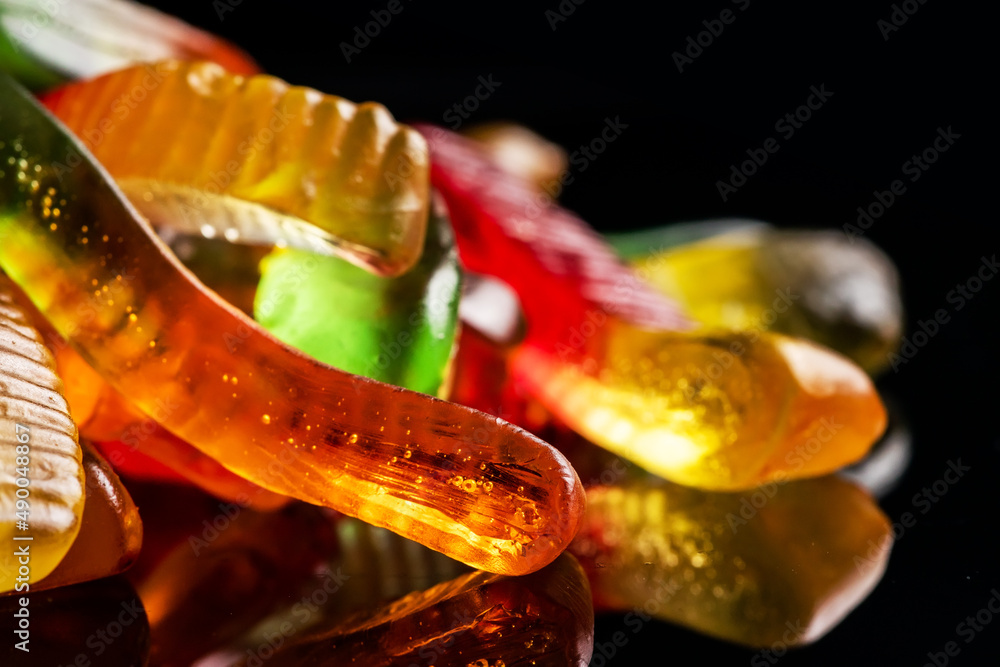 Sticker Juicy colorful jelly worms sweets. Gummy candies. Snakes. On black backgriund