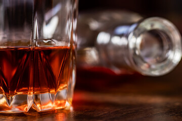 A glass of whiskey and a bottle lying on the table