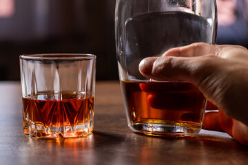 Alcoholism, man hand takes a bottle of alcohol, holding bottle of whiskey alone. Treatment of alcohol addiction, suffer abuse problem alcoholism concept