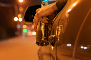 Drunk man driving a car with a bottle of beer at the night. Don't drink and drive concept