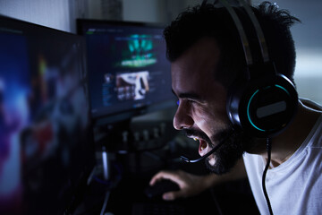 a young 30-year-old gamer is sitting at a computer, playing computer games, nervous, angry,...