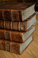 Dusty, worn and faded leather-bound Jewish holy books stacked upright on a library shelf.