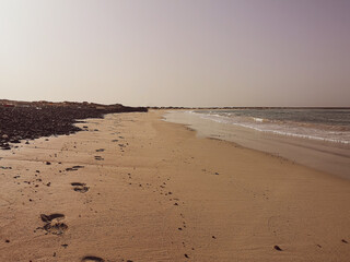 Sandy beach on Boa Vista Island, Cape Verde. Romantic coastline view, footprints in the sand, sunny afternoon. Selective focus on the details, blurred background.