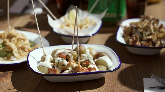 Video of close up of group of friends eating different plates of food in a terrace at restaurant.
