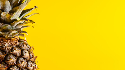 Beautiful fresh pineapple isolated on yellow background. Summer seasonal fruit design idea pattern concept. Copy space, close up