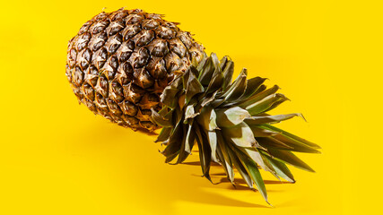 Beautiful fresh pineapple isolated on yellow background. Summer seasonal fruit design idea pattern concept. Copy space, close up