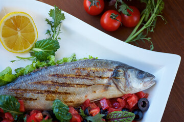 Whole grilled fish with vegetables. The concept of a menu for a restaurant or cafe.