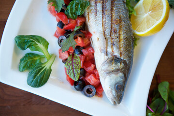 Whole grilled fish with vegetables. The concept of a menu for a restaurant or cafe.