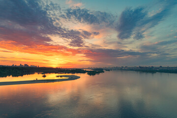 Spectacular sunrise sky over river. Skyscrapers in the city in the background.