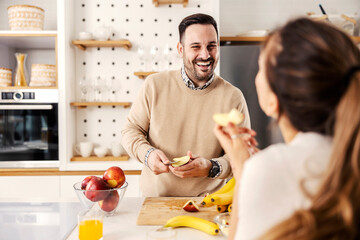 A man cutting apples in the kitchen for a snack for his wife at their cozy apartment.