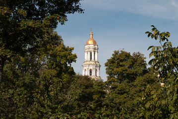 Fototapeta na wymiar Bell tower in the green forest. Kiev-Pechersk Lavra. Kyiv. Ukraine 