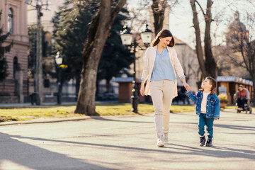 A happy mother and little boy holding hands in a walk and enjoying sunny day.
