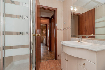 Bathroom with shower cabin with sink cabinet with marble top and white porcelain sink with square glass mirror