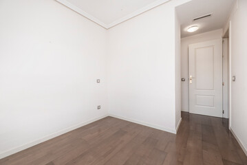 Empty room with dark wooden floors, white painted walls and white lacquered woodwork