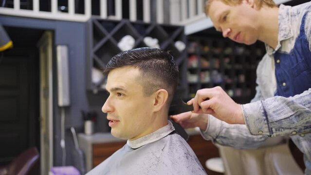the hairdresser makes a haircut for a man with a hair clipper in a barbershop