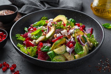 Salad with avocado, beetroot, feta, nuts and pomegranate close-up.